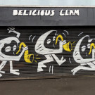 Shop shutters painted with three clam characters, each playing a saxophone in different poses